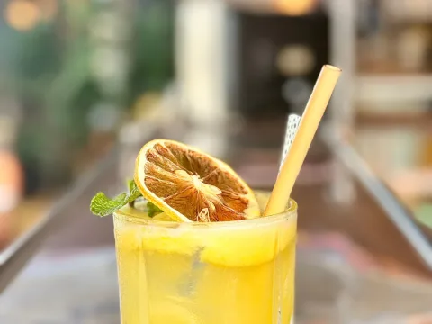 Un cocktail jaune à la rondelle d'orange séchée et à la menthe, posé sur le comptoir