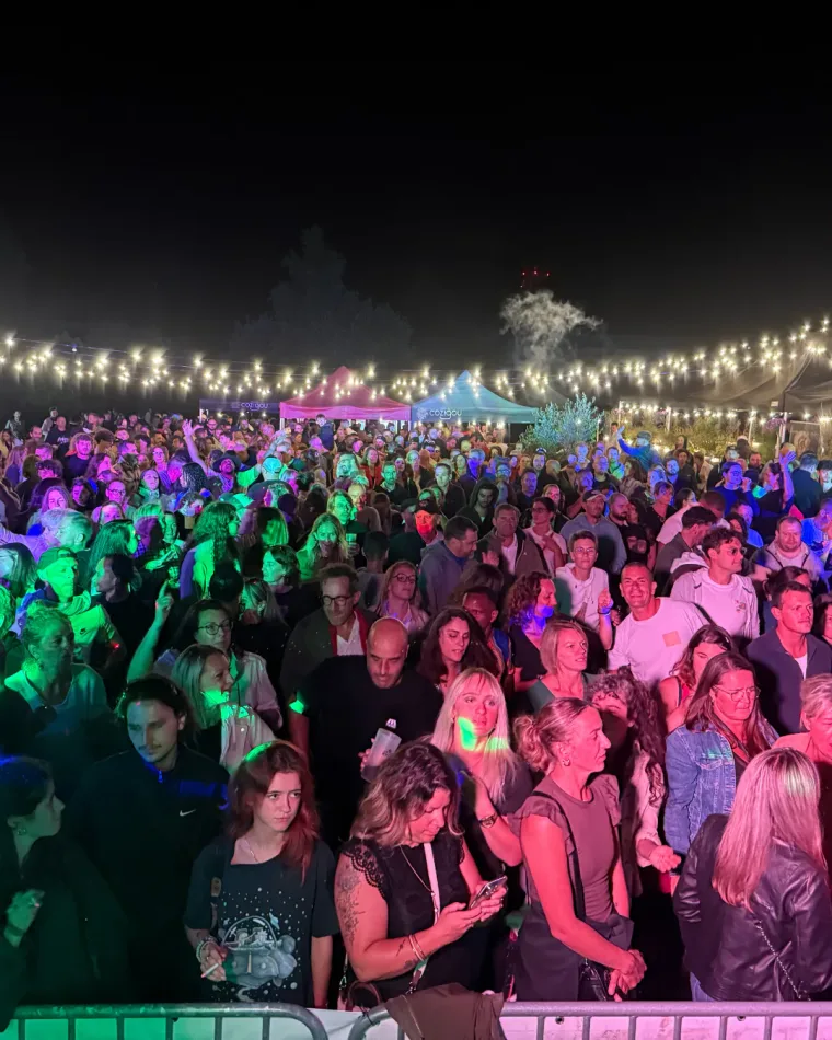 La foule d'une soirée en plein air, de nuit, sous les guirlandes et les projecteurs