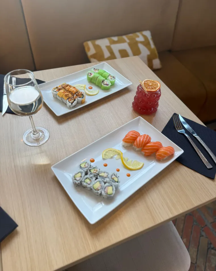 Sushis au saumon et californias à l'avocat servis sur assiettes, avec un cocktail rouge